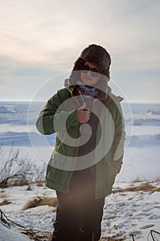 Woman in sunglasses giving thumbs up at on frozen lake shore