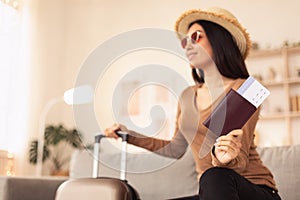 Woman In Sunglasses Holding Tickets Sitting On Sofa At Home