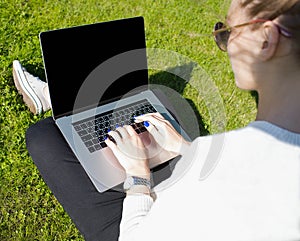 Woman in sunglasses lifestyle writer keyboarding on laptop computer with copy space on screen.