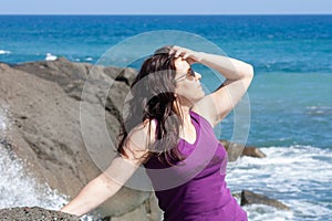 woman with sunglasses posing on the beach and leaning on rocks