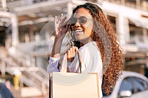 Woman, sunglasses and shopping bag in city for sale discount or fashion retail, product or promotion. Female person