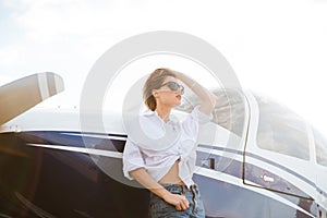 Woman in sunglasses standing outdoors near small private plane