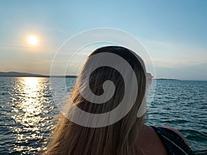 Woman with sunglasses staring at the sea at beautiful sunset