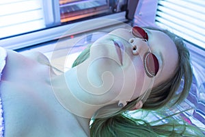 Woman with sunglasses on tanning bed in solarium