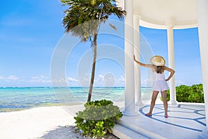 Woman in a sunhat enjoying a scenic Caribbean beach resort while on vacation.