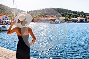 A woman with sunhat looks over the sailing marina at Fiskardo, Kefalonia, Greece