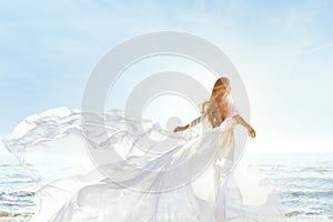 Žena na slnečný more pláž v biely vlajúce šaty móda zadná hodváb tkanina mávanie na vietor 