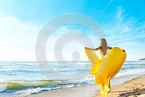 Woman on Sunny Sea Beach in Yellow Fluttering Dress, Fashion Model Back Rear View, Silk Cloth Waving on Wind