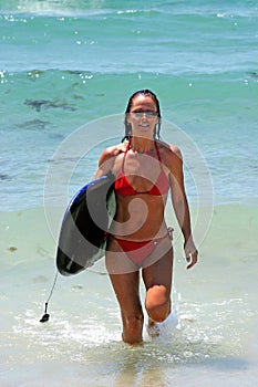 Woman on sunny Spanish beach in sea after surfing and body boarding