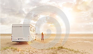 Woman at sunset  with mobile home on the beach photo