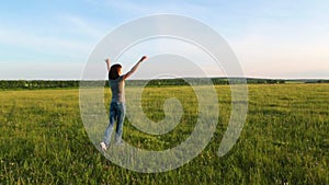 Woman at sunset raises her hands up and enjoys a beautiful warm sunny evening