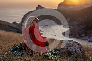 Woman sunset sea mountains. Happy woman siting with her back on the sunset in nature summer posing with mountains on