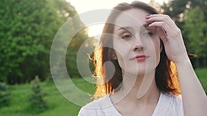 Woman at sunset straightens hair. Slow motion.