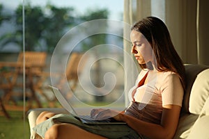 Woman at sunset using laptop at home