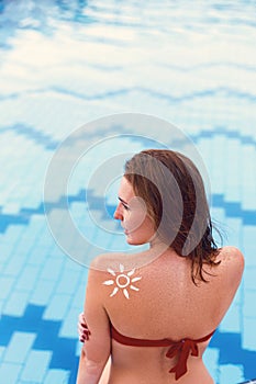 Woman With Suntan Lotion At The Beach In Form Of The Sun. Portraita Of Female With the Drawn Sun On a Shoulder On The Pool