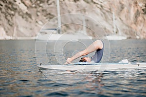 Woman sup yoga. Middle age sporty woman practising yoga pilates on paddle sup surfboard. Female stretching doing workout