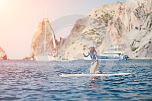 Woman sup yoga. Middle age sporty woman practising yoga pilates on paddle sup surfboard. Female stretching doing workout