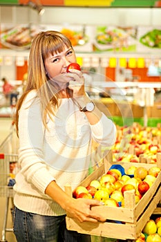 woman in a supermarket with a box of red apples in her hands