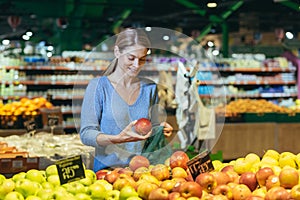 A woman in a supermarket, a buyer chooses an apple fruit,