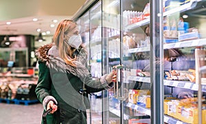 Woman at supermarket freezer section wearing face mask