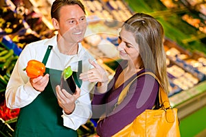 Woman in supermarket and shop assistant