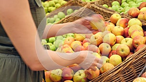 A woman in a supermarket on a vegetable shelf, buys vegetables and fruits. Man chooses apples. Slow motion, 4k