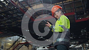 Woman supervisor holding tablet computer at huge modern manufacturing storage.