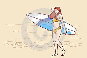 Woman surfer dressed in bikini walks along beach with surfboard and enjoys summer trip to island