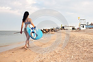 Woman surfer with surfboard going to surf at seaside. Girl holding surfboard o and goes to the ocean sea, a view from