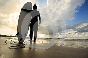 woman surfer with surfboard on sunrise beach