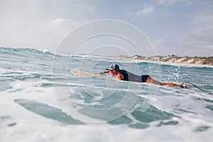 Woman surfer swimming in sea