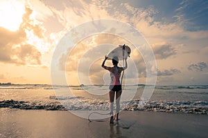 Woman surfer with white surfboard walking to the sea