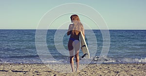 Woman with Surfing Board Walking at the Beach