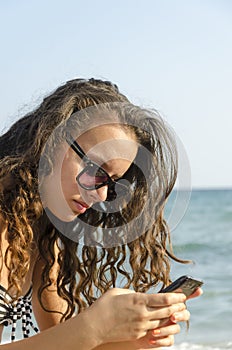 Woman is surfing on smartphone sitting on beach