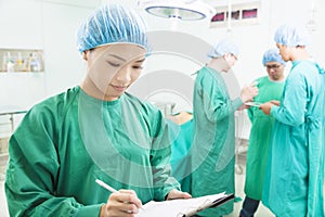 Woman Surgeons writing medical record with teams