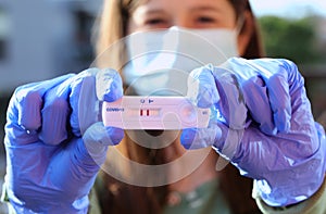 Woman with surgical mask holds coronavirus diagnostic test between latex gloves after successful test photo