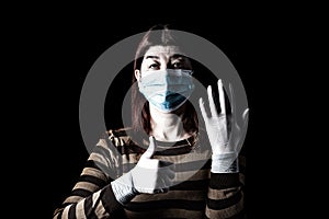 Woman with surgical mask, protective gloves and thumbs up. Pandemic or epidemic and scary, fear or danger concept. Protection for