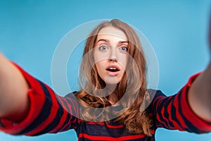 Woman with surprised facial expression taking selfie, point of view of photo, posing with open mouth