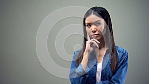 Woman suspecting something, thinking about cunning plan on grey background