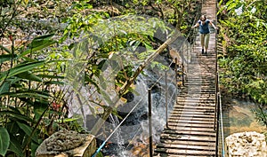 Woman on a suspension bridge over a waterfall in the rainforest of Paraguay. photo