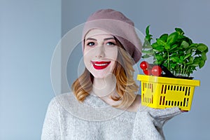 Woman in sweater and beret with basket of herbs