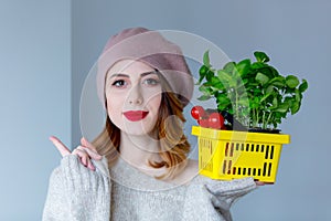 Woman in sweater and beret with basket of herbs