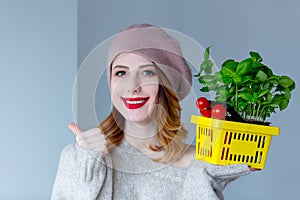 Woman in sweater and beret with basket of herbs