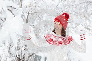 Woman in sweater playing snow ball fight in winter