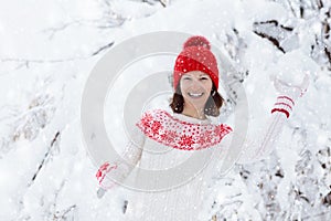 Woman in sweater playing snow ball fight in winter