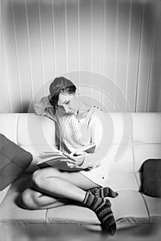 Woman in sweater reading a book on sofa
