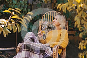 woman in sweater reads book and drinking wine in terrace