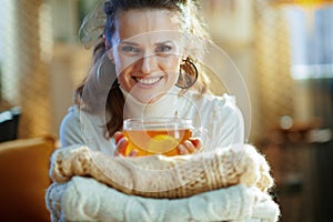 Woman with sweaters and tea at modern home in sunny winter day