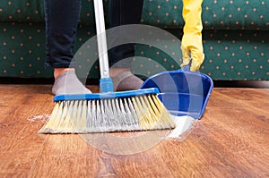 Woman sweeping floor with broom and dustpan