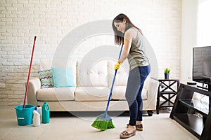 Woman sweeping floor feeling happy